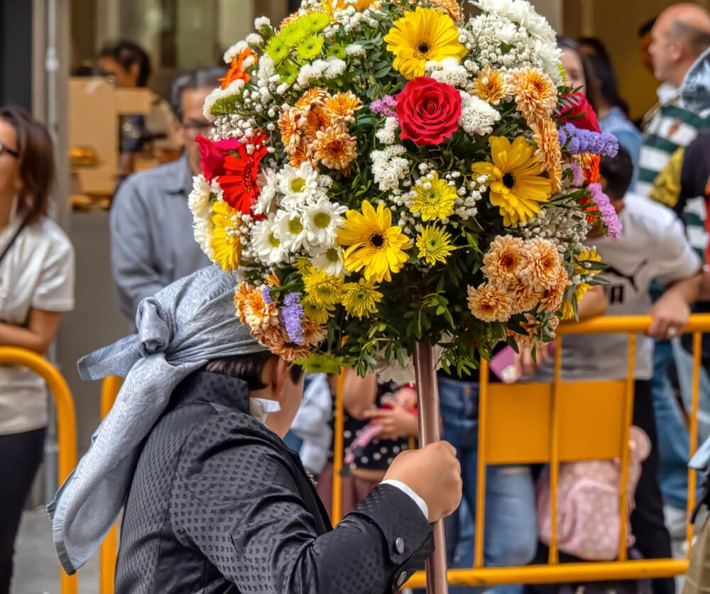 A boy carries an offering of flowers during a Valencian festival