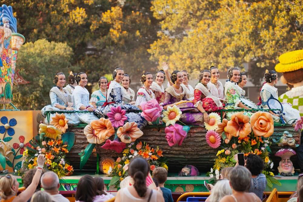 Women in traditional fallera dress sit atop a float during the Cabalgata del Foc