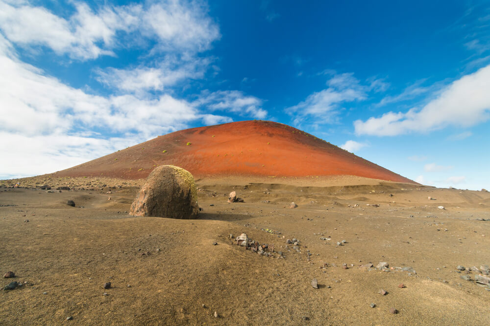 Family holidays in Lanzarote: Sandy landscape with a red sandy hilly volcano in the distance