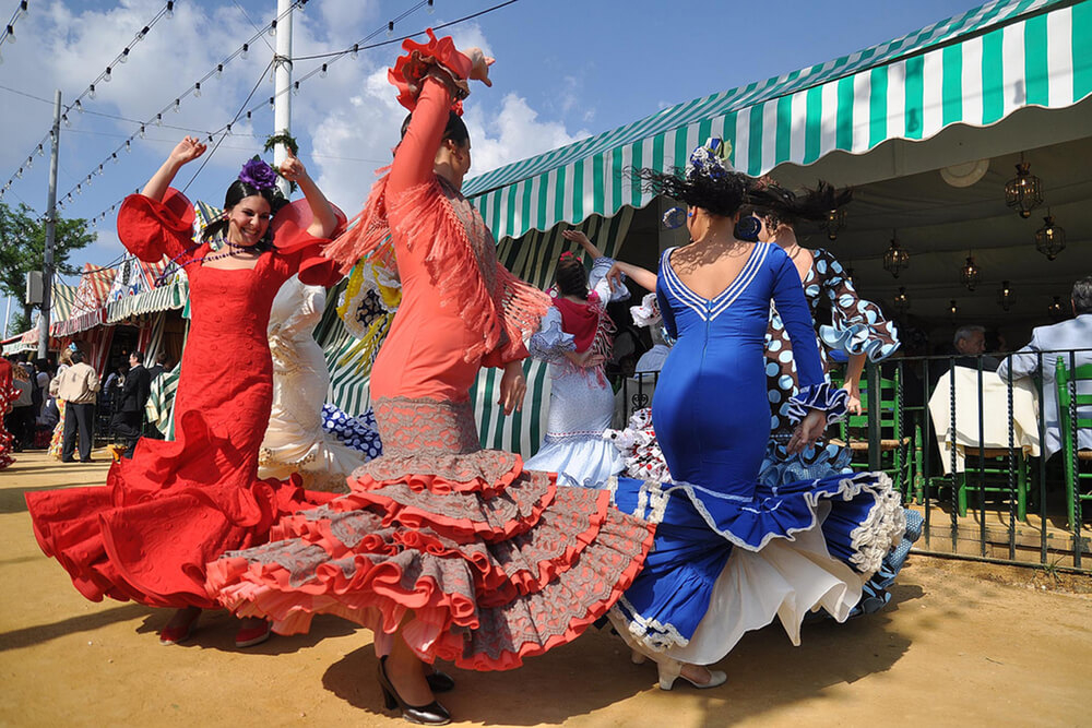 Feria Andalusien: Frauen tanzen in Flamenco-Kleidern auf der Feria de Abril in Sevilla.