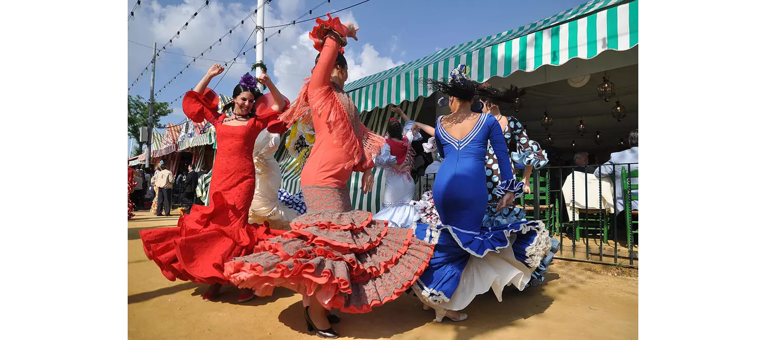 Feria Andalusien: Frauen tanzen in Flamenco-Kleidern auf der Feria de Abril in Sevilla.