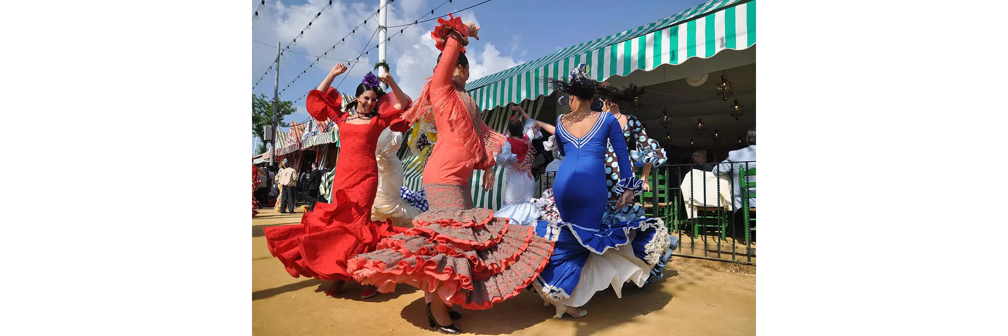Feria Andalusien: Frauen tanzen in Flamenco-Kleidern auf der Feria de Abril in Sevilla.