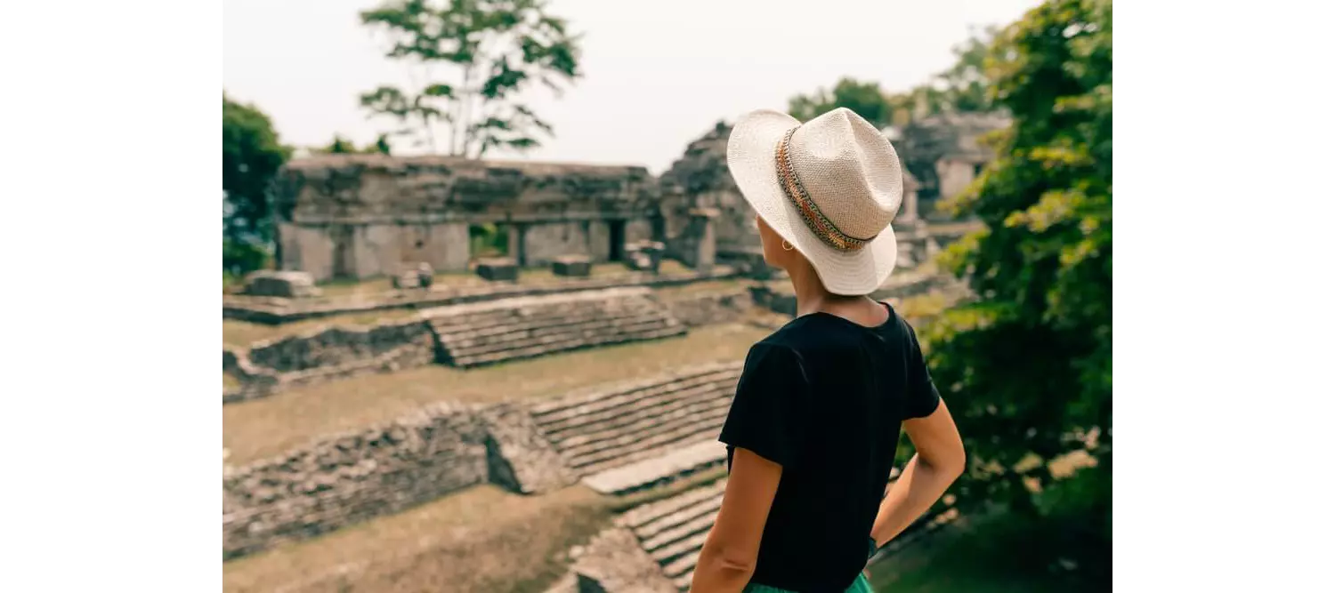 A woman wearing a hat while exploring Mayan ruins.