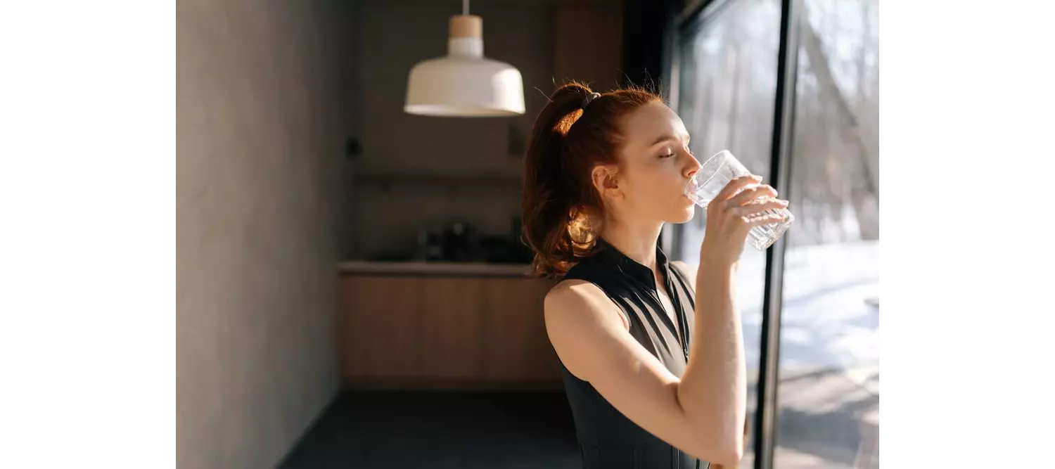 A woman drinking water to stay healthy on a fitness vacation 