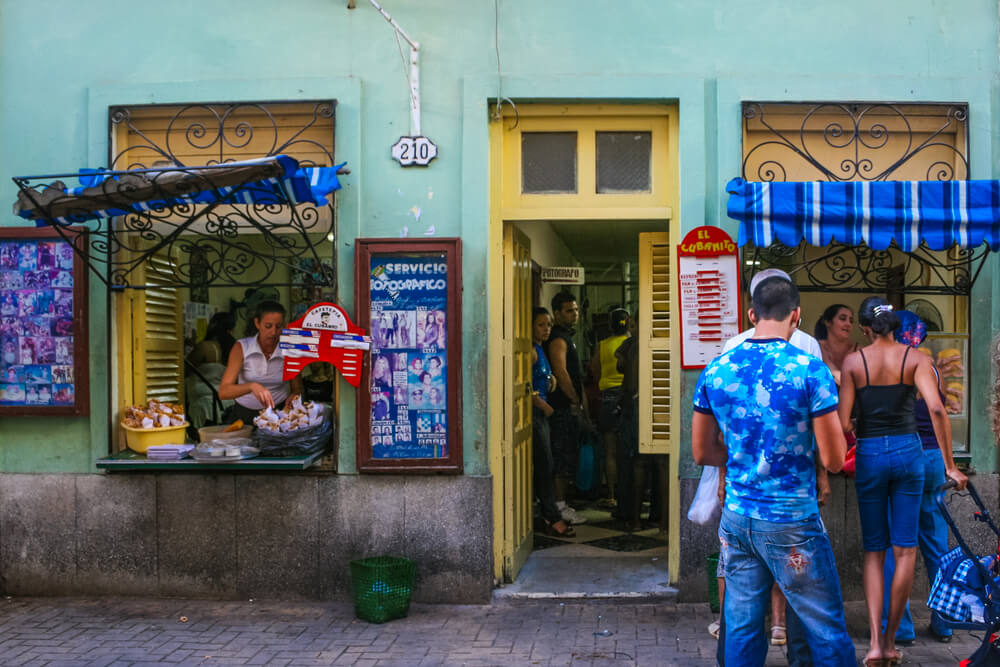 Cuban bars: A blue cafeteria bar serving food to a group of people