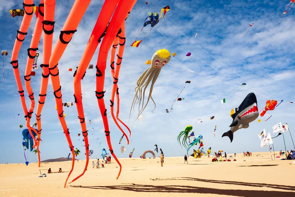 Fuerteventura family holidays: A beach full of different shaped kites flying in the wind