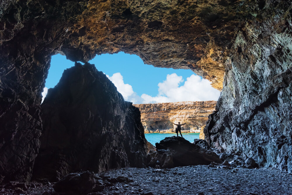 Mensch am Rande einer der Höhlen von Ajuy auf Fuerteventura mit Blick aufs Meer.