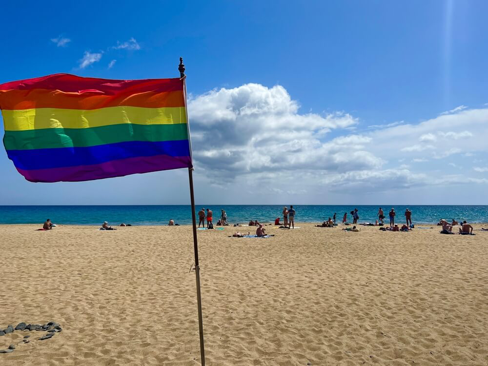 Gay Pride fest: Golden beach of Maspalomas with LGBT flag in the sand