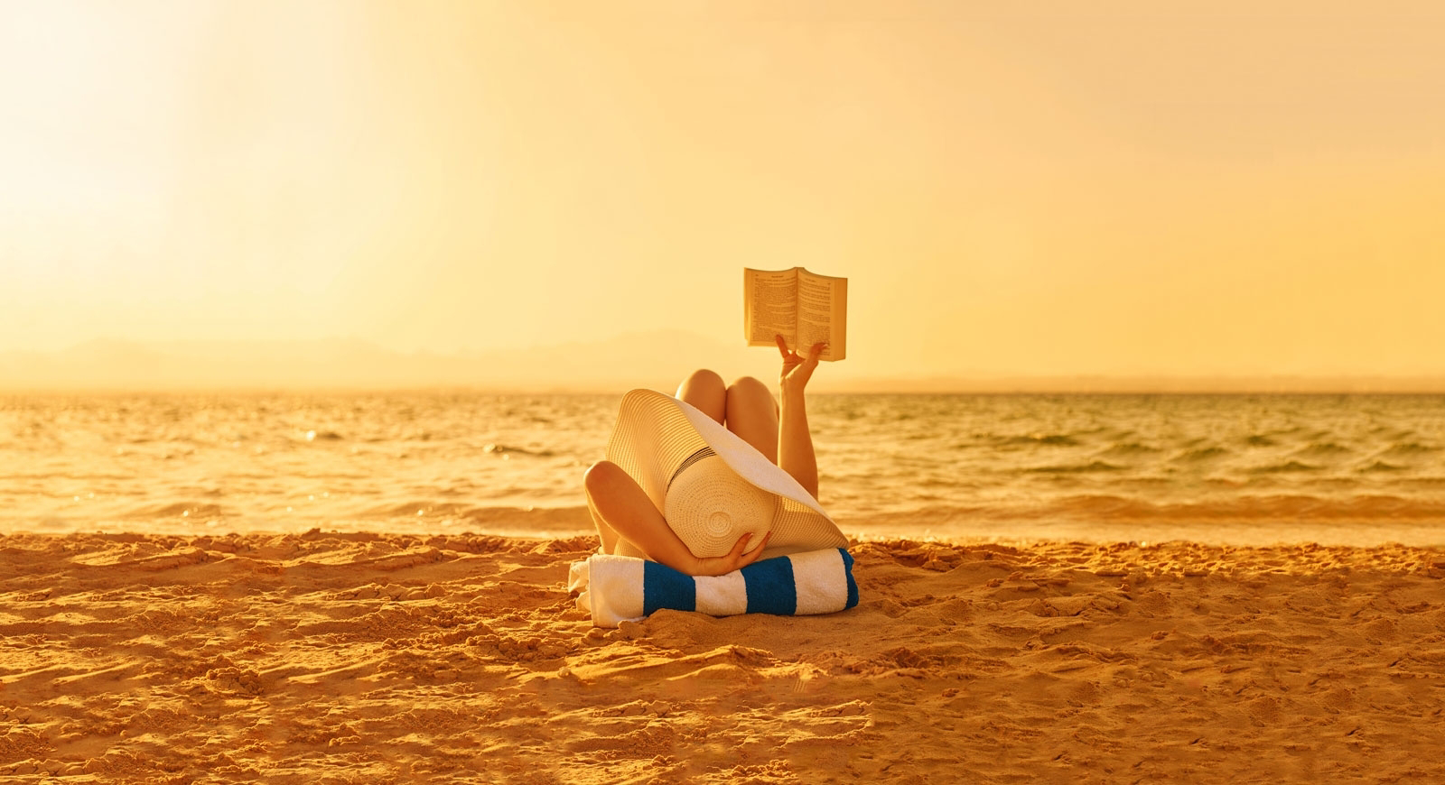 Happy place: Woman reading a book on the beach