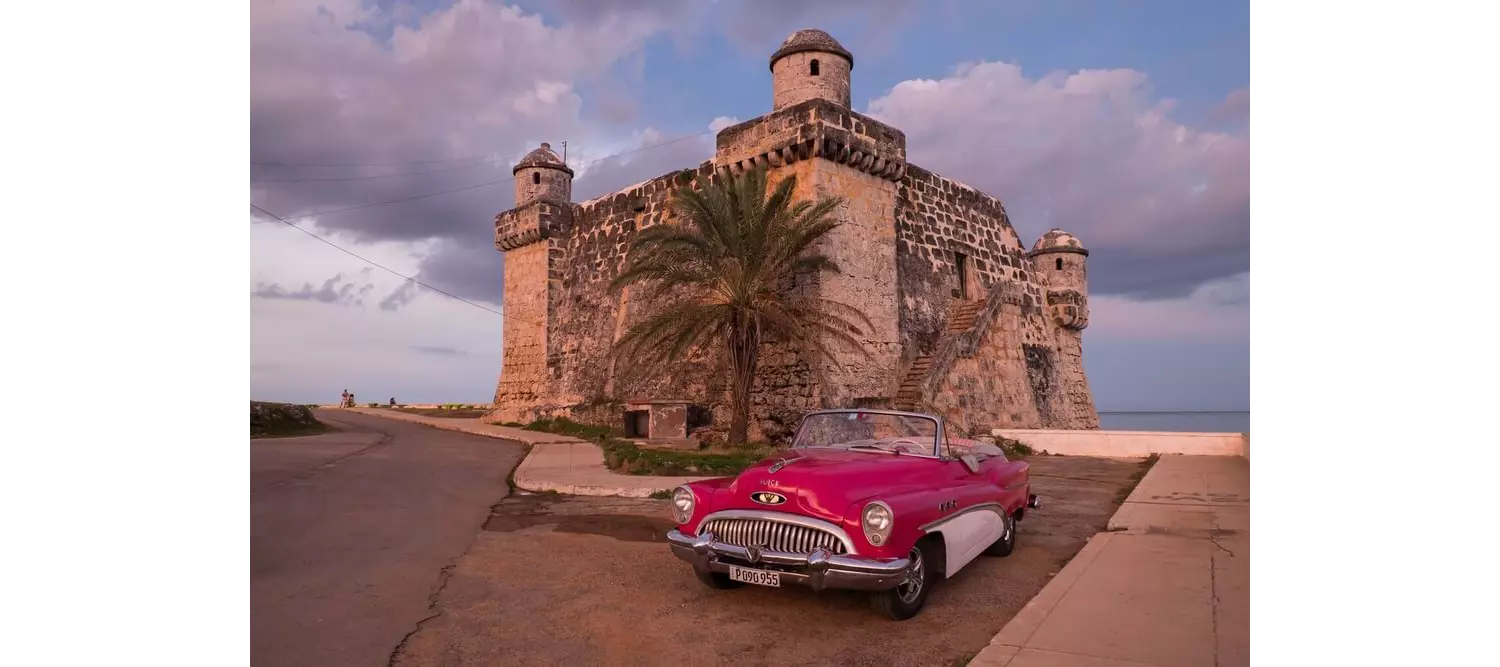 Cojímar: a close-up of a red car and an old tower at sunset