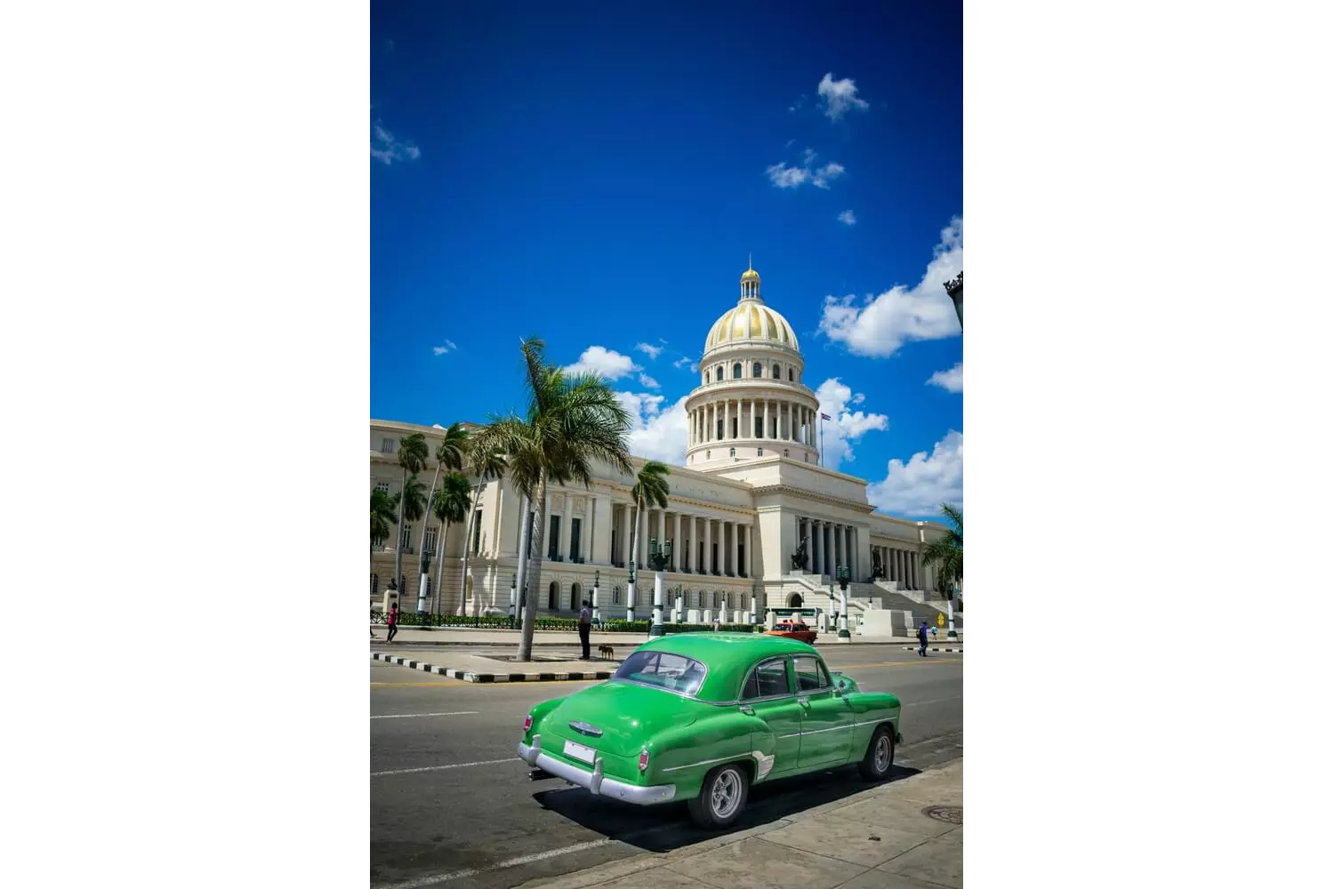 Hemingway Cuba: A street view of a typical main street with a state building and green car