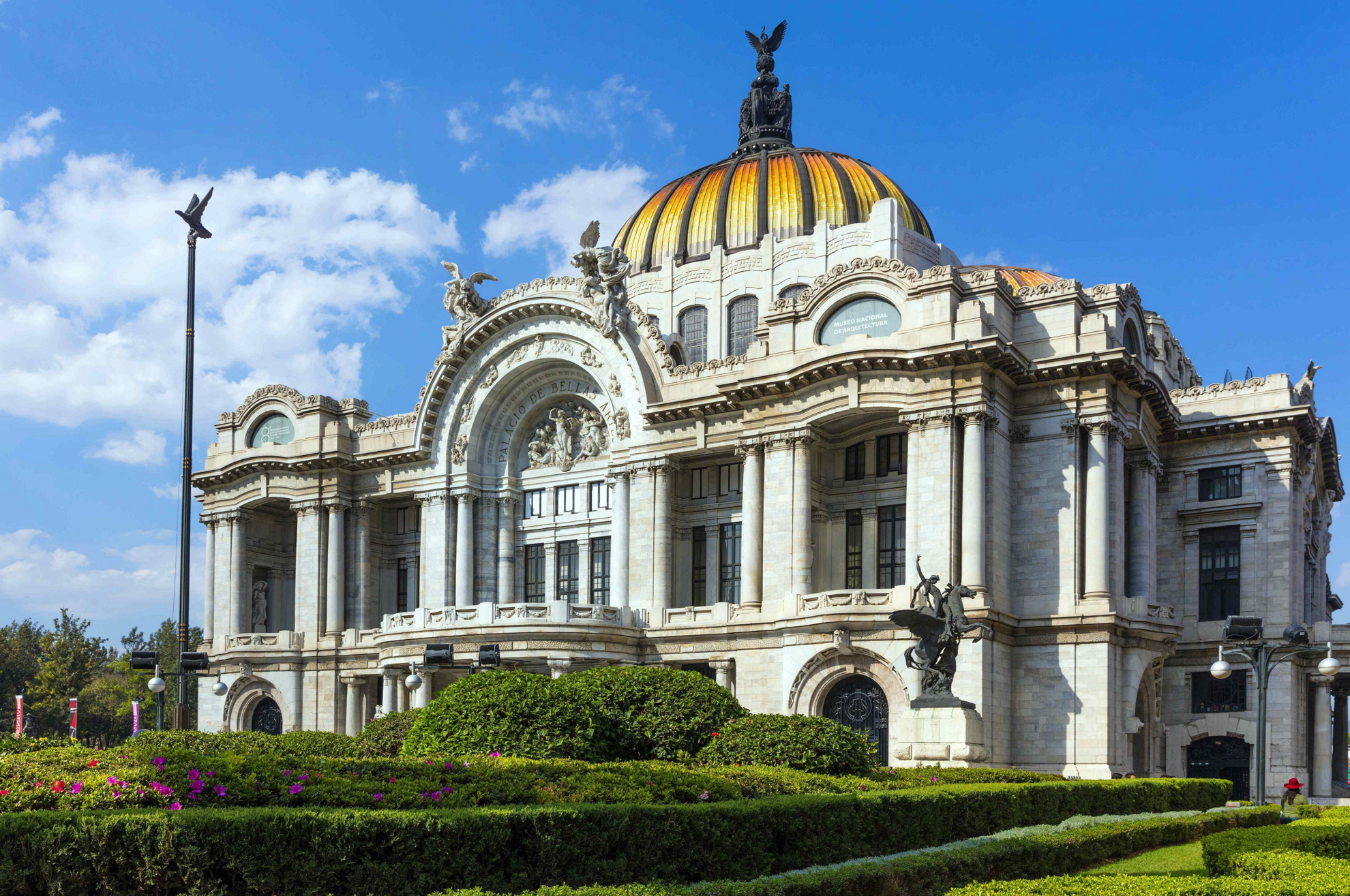 Photo of the facade of Palacio de Bellas Artes in Mexico City against a blue sky.