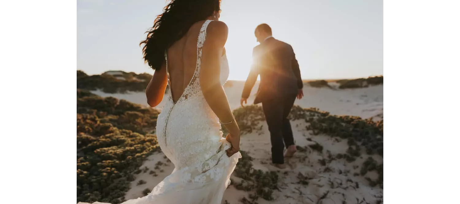 Hochzeit im Freien: Brautpaar geht über Felsen in Strandnähe.