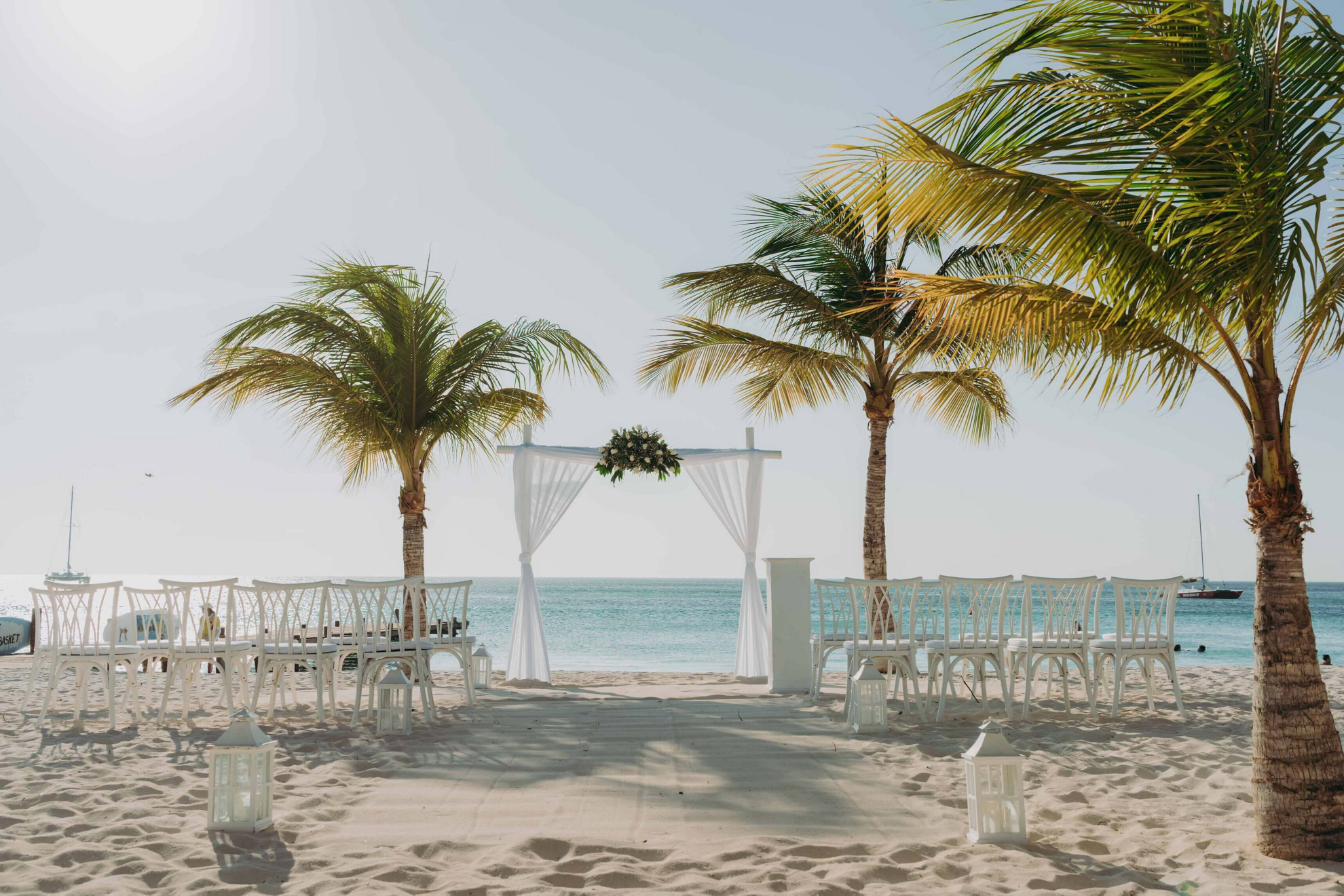 Palmenstrand, der mit Stühlen und Altar für eine Hochzeit vorbereitet ist.