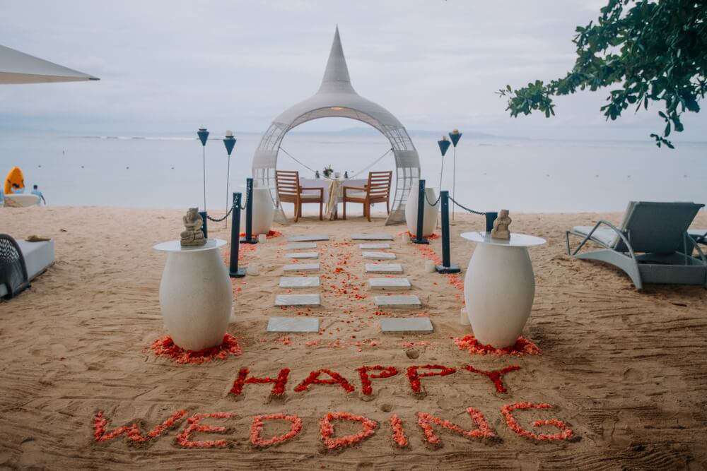 Hochzeitsaltar an einem Strand, auf den “Happy Wedding” geschrieben steht.