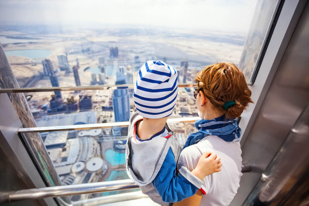 Travelling with a baby: Mother with child in arms looking out over Dubai