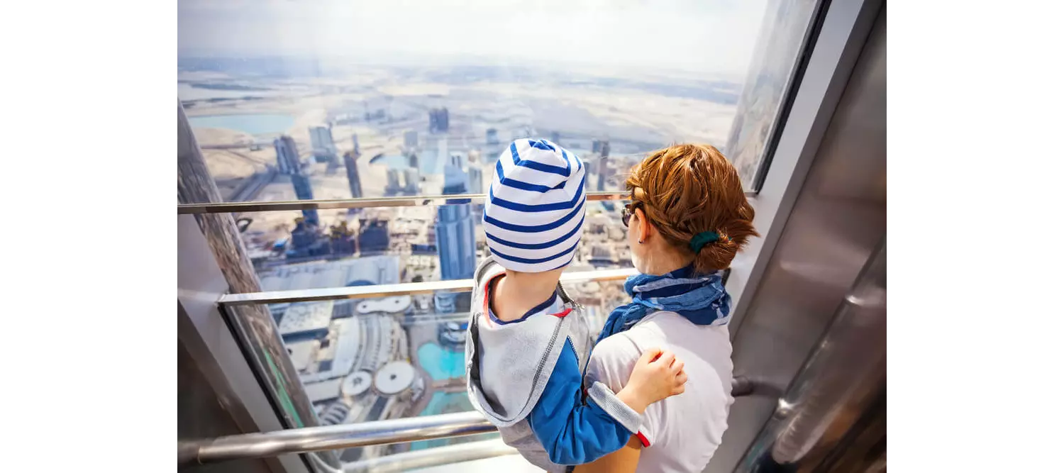 Travelling with a baby: Mother with child in arms looking out over Dubai