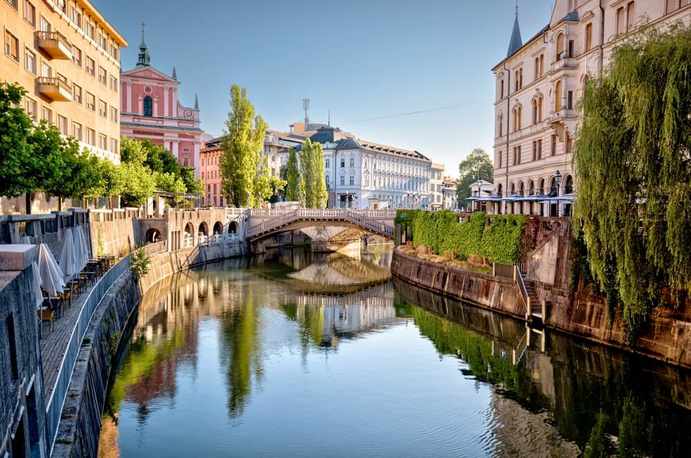 A view of Ljubliana, with beautiful buildings and riverside terraces reflected in the water