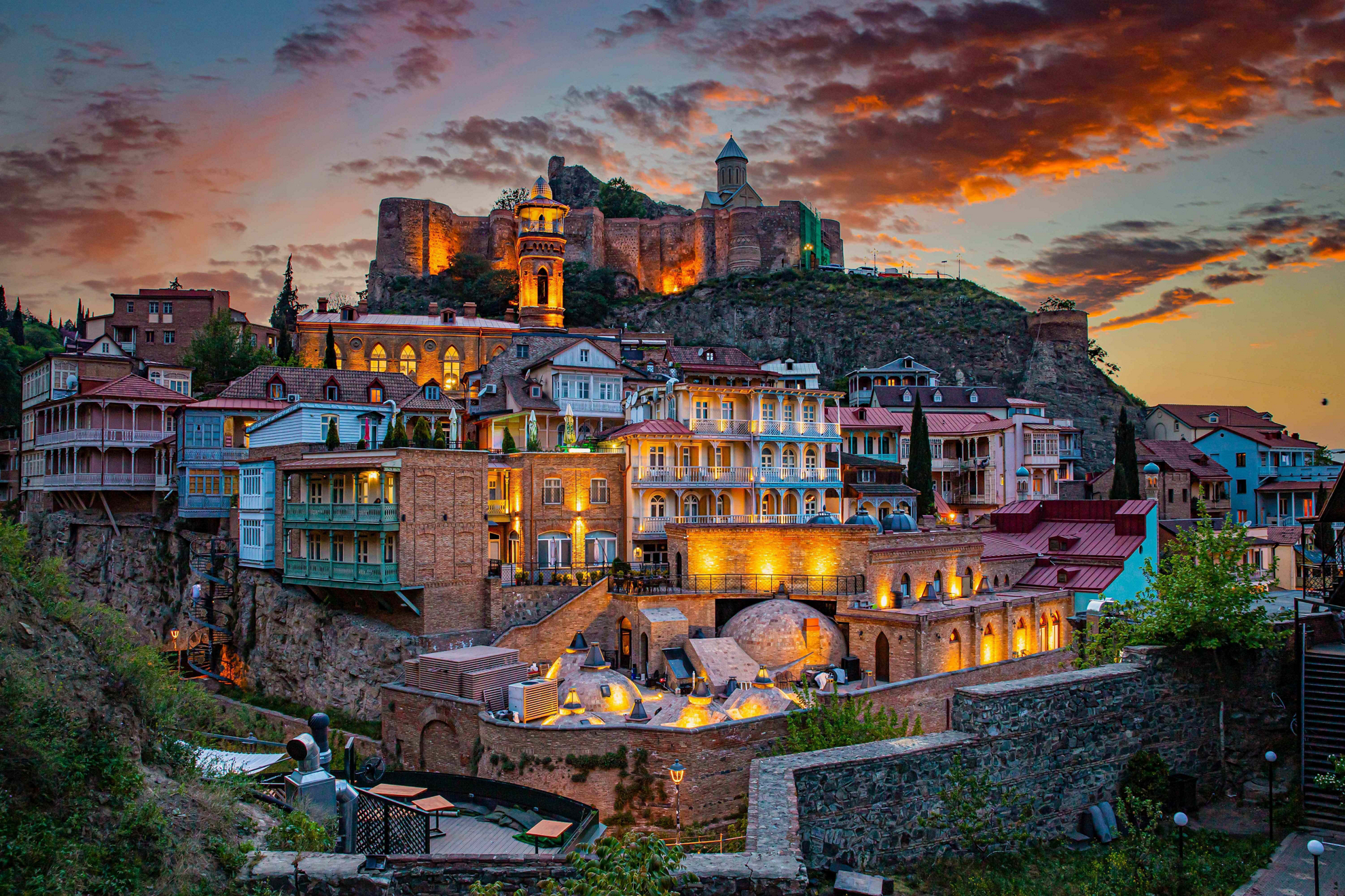 Holidays to Georgia: Buildings on a cliffside lit up at night