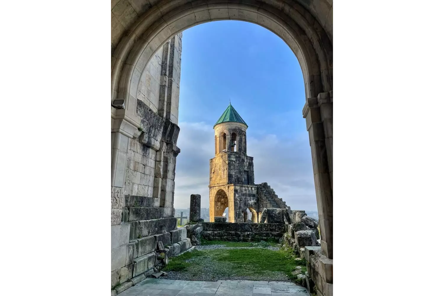 Kutaisi: A grey stone cathedral bell tower with a green turret