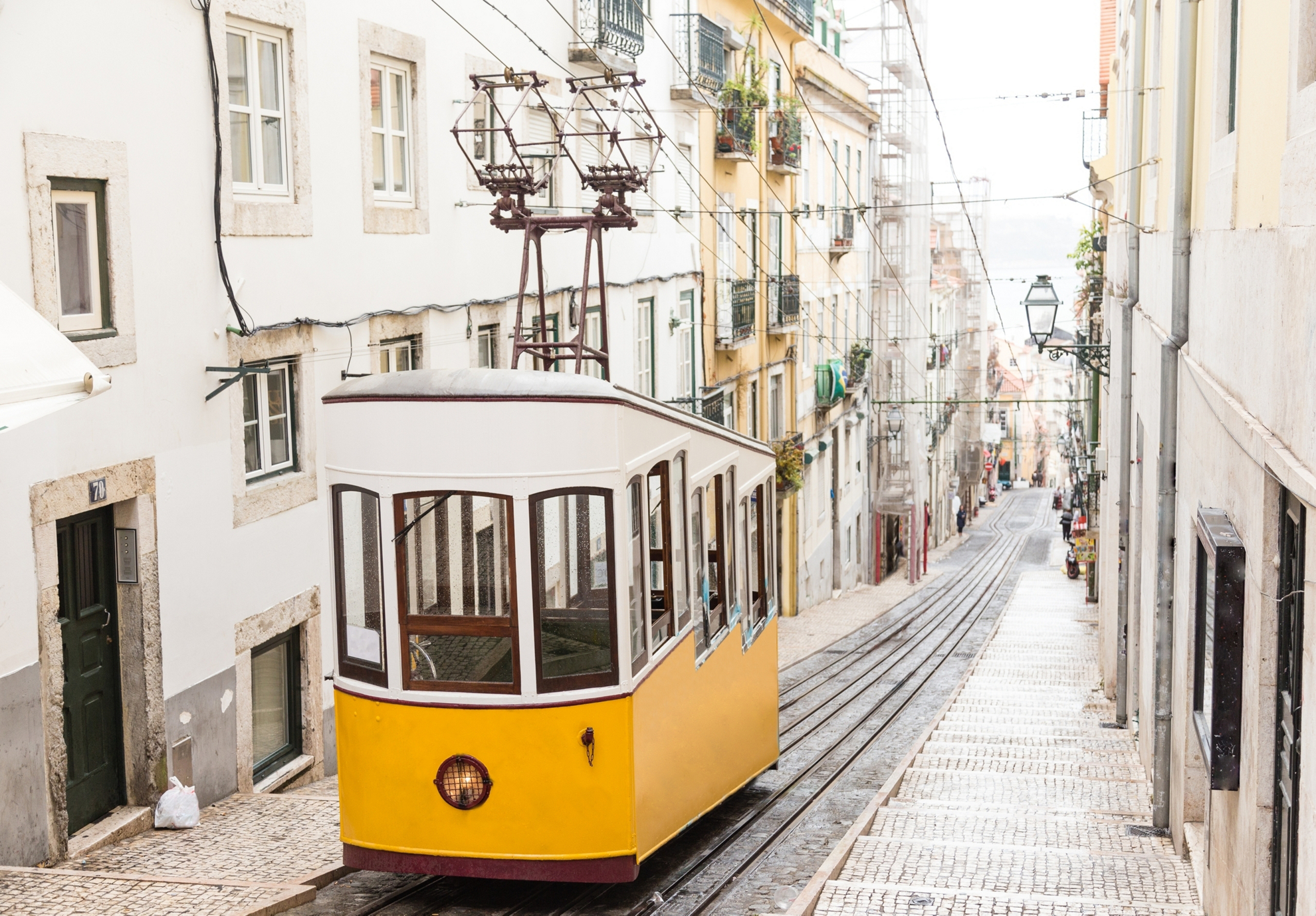 Typical yellow old tram funicular Elevador da Bica in Bairro Alto, going up hill in the old town of Lisbon