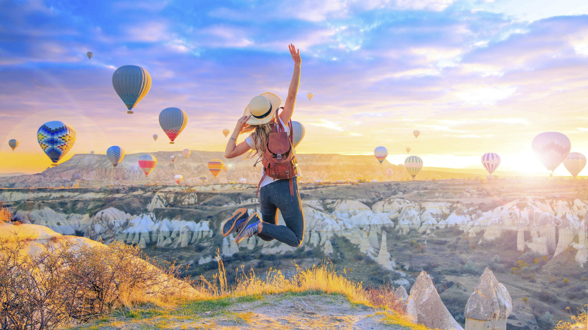 Instagrammable locations: Woman jumping in the air with hot air balloons in the background