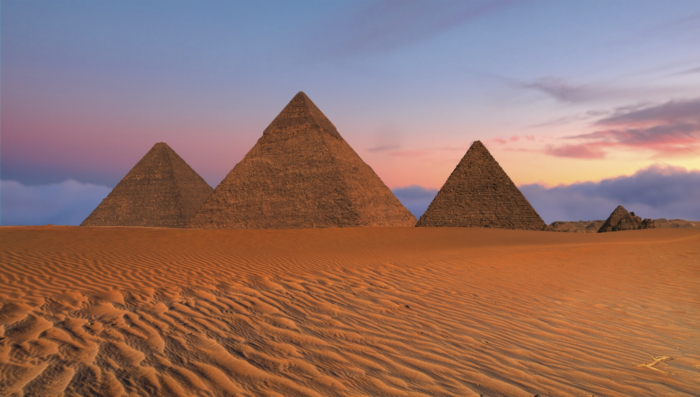 Pyramids of Giza: Three pyramids standing in the desert of Cairo at sunset