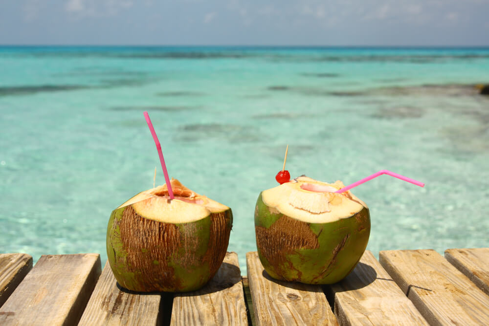 Zwei Karibik-Drinks am Strand in ausgehöhlter Kokosnuss serviert