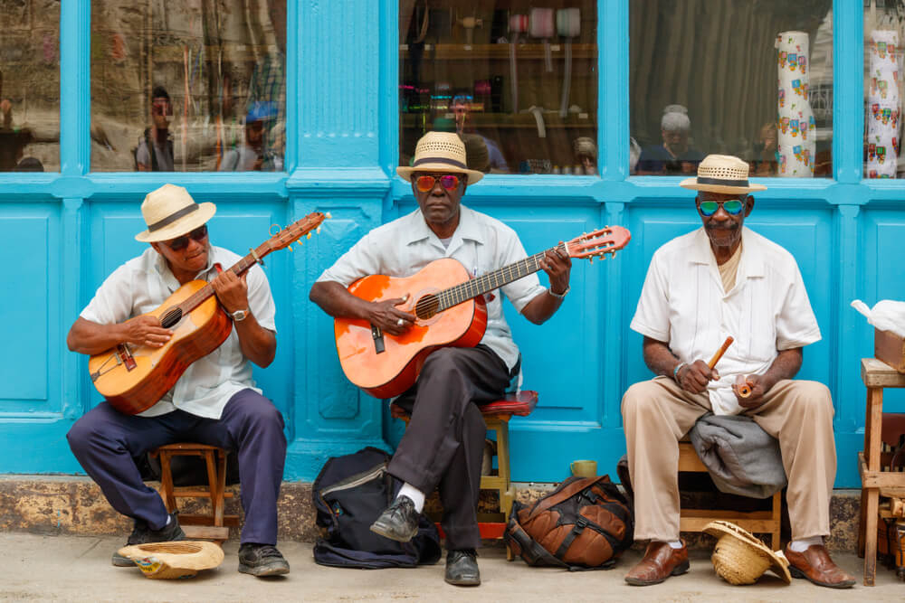 Kuba Kultur: drei Straßenmusiker vor einer blau bemalten Fassade.