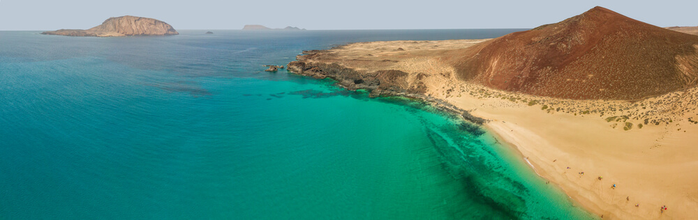 Blick auf den Playa de Montaña Bermeja auf Lanzarote mit Eilanden im Hintergrund.