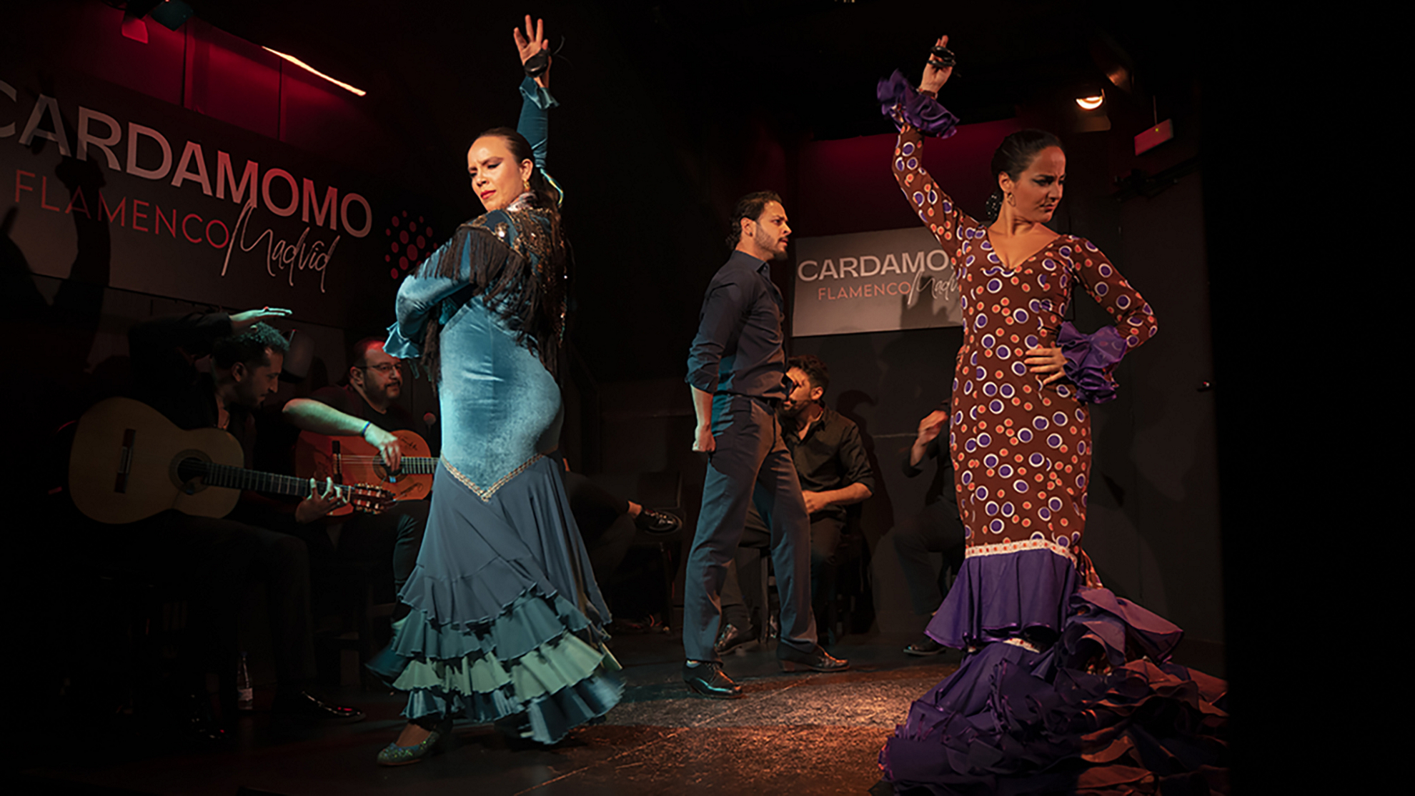 Cardamomo: Two women dressed in flamenco dresses dancing on stage