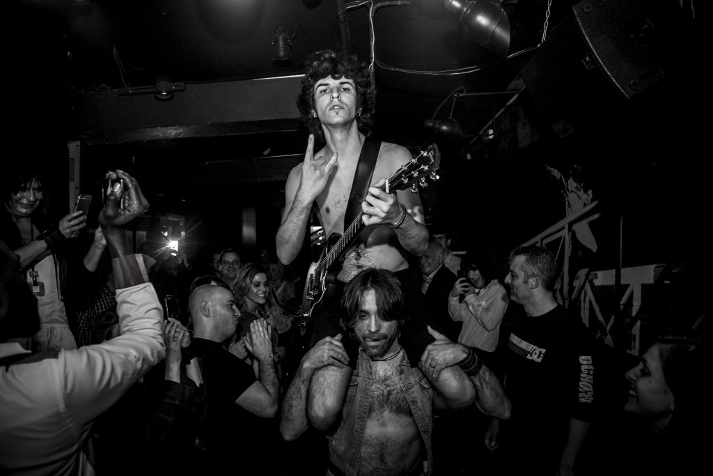 Live music in Madrid: Black and white photo of men partying at a rock concert