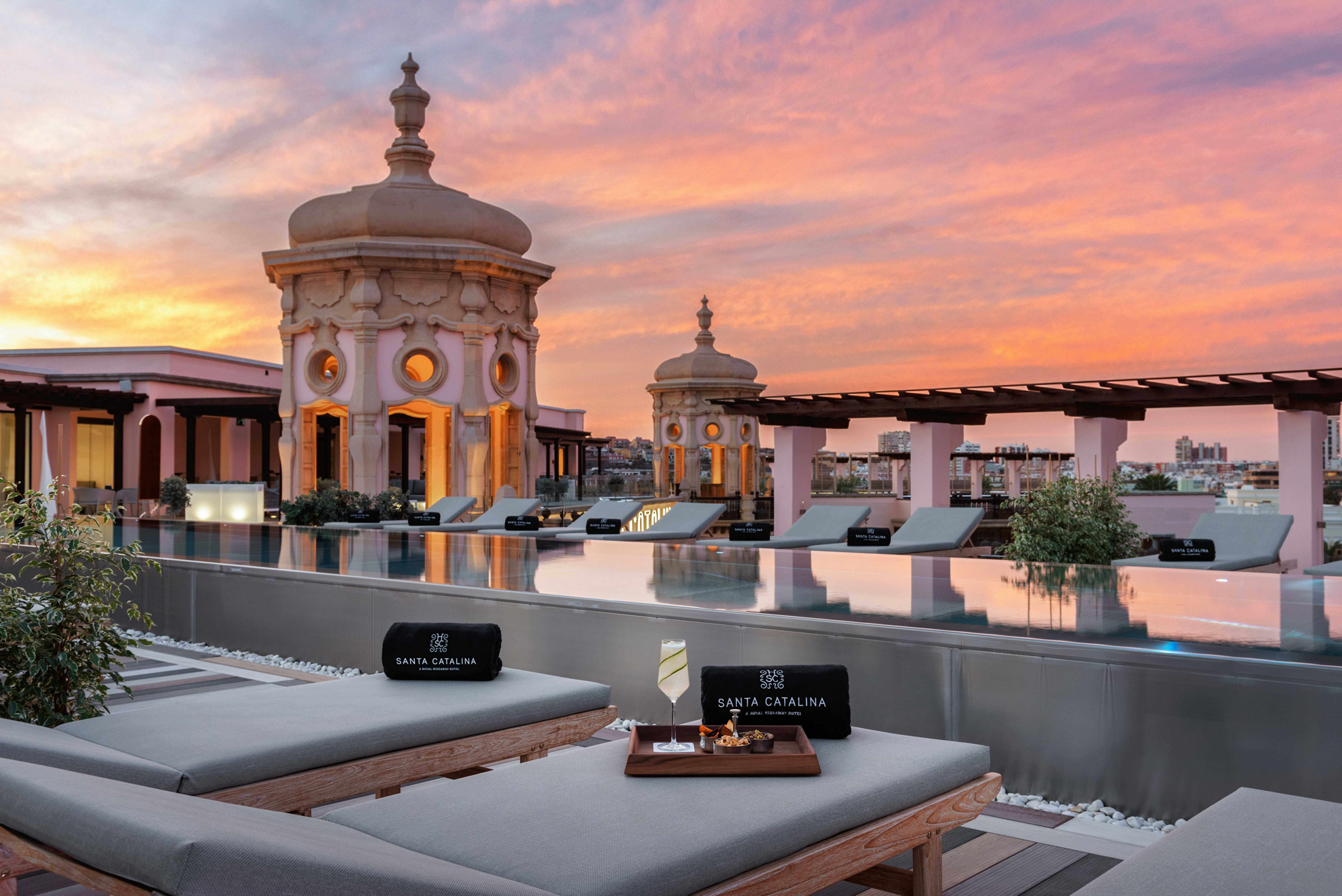Luxury holidays Gran Canaria: A pool with two sunloungers overlooking a turreted rooftop at sunset