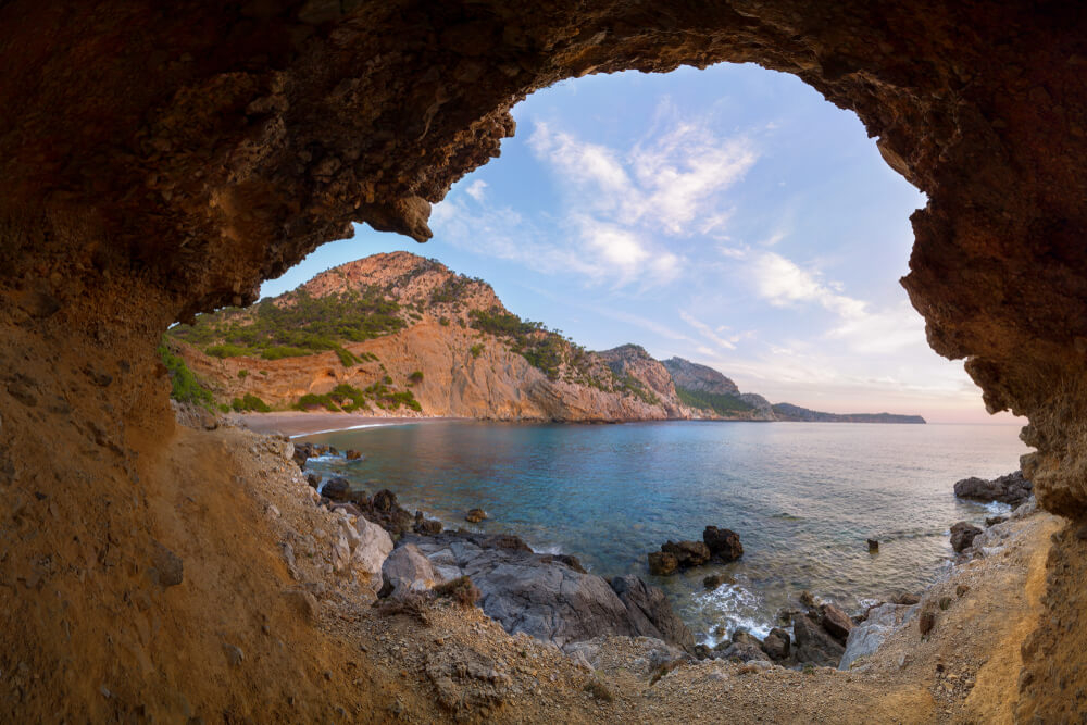 Mallorca Calas: Blick durch Felsen auf die Bucht Coll Baix.