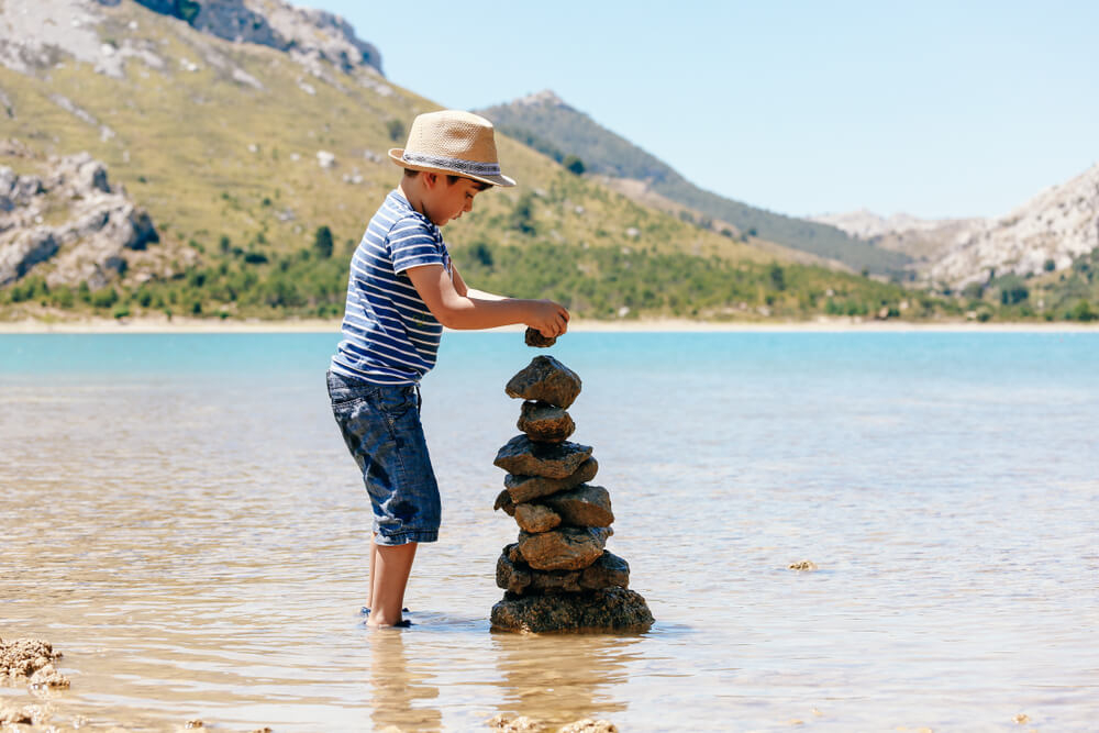 Serra de Tramuntana: A boy making a tower of stones on the beach