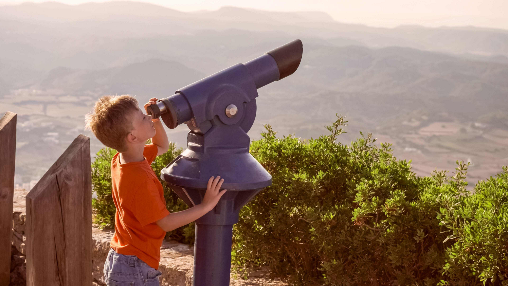 Menorca mit Kindern entdecken: Junge an einem Fernglas auf dem Monte Toro.