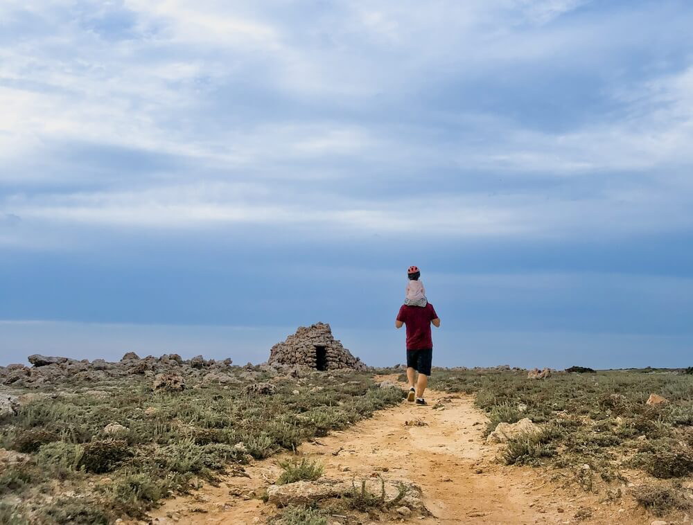 Wandern auf Menorca mit Kindern: Vater trägt sein Kind auf dem Rücken.