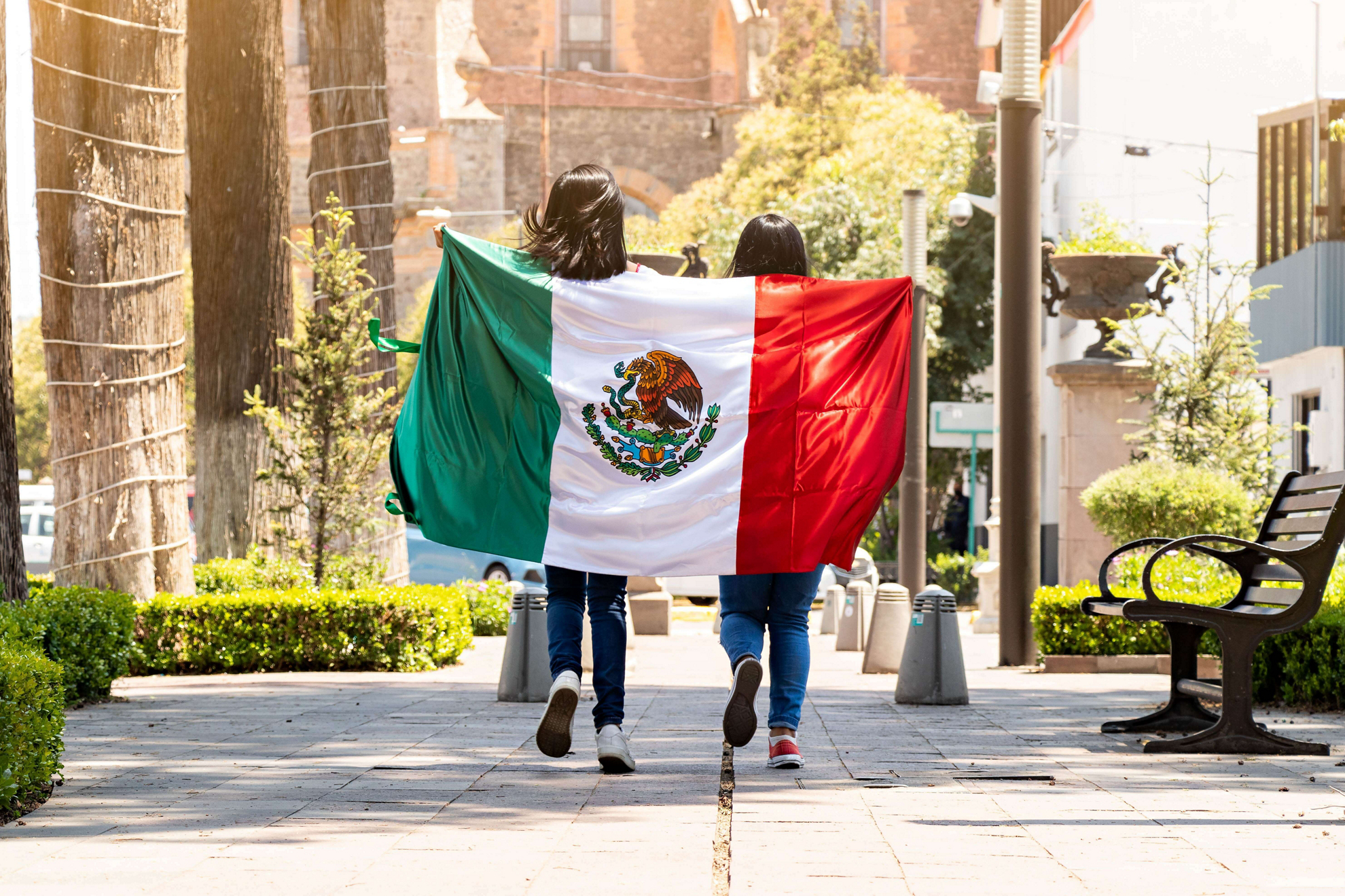Two girls walking in the street with the Mexican flag 