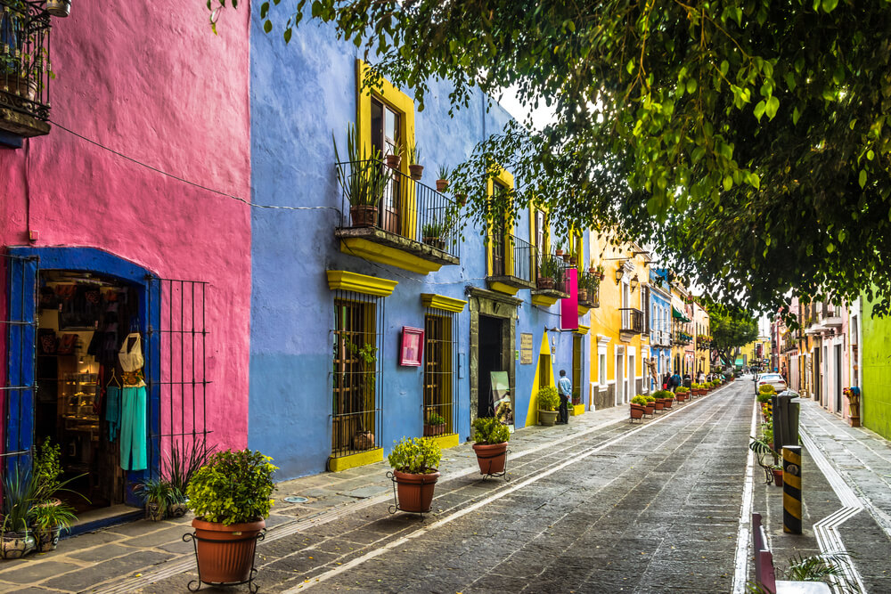 An old street in Puebla, Mexico, is lined with colorful storefronts and homes. 
