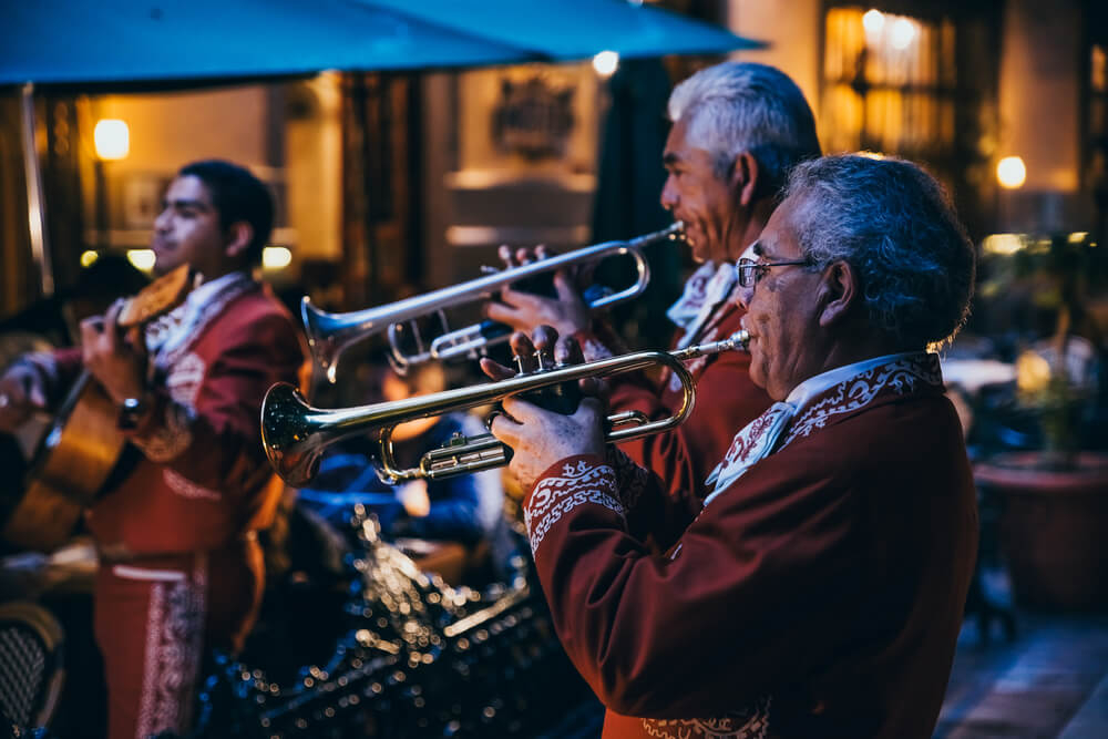 Two men in a mariachi group play their trumpets proudly in the streets of Mexico.
