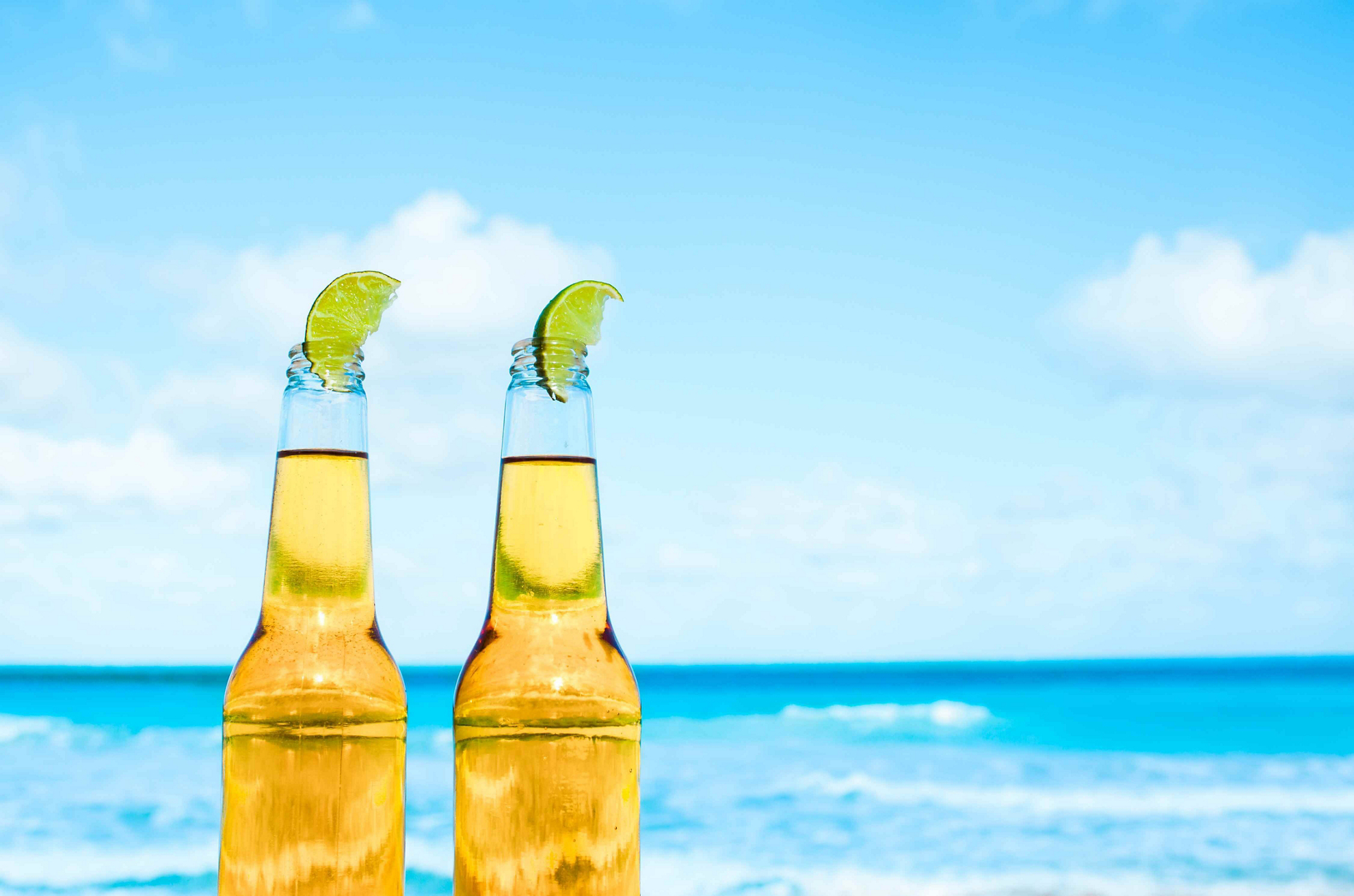 Mexikanisches Bier: zwei Bierflaschen mit Limettenscheiben am Strand.