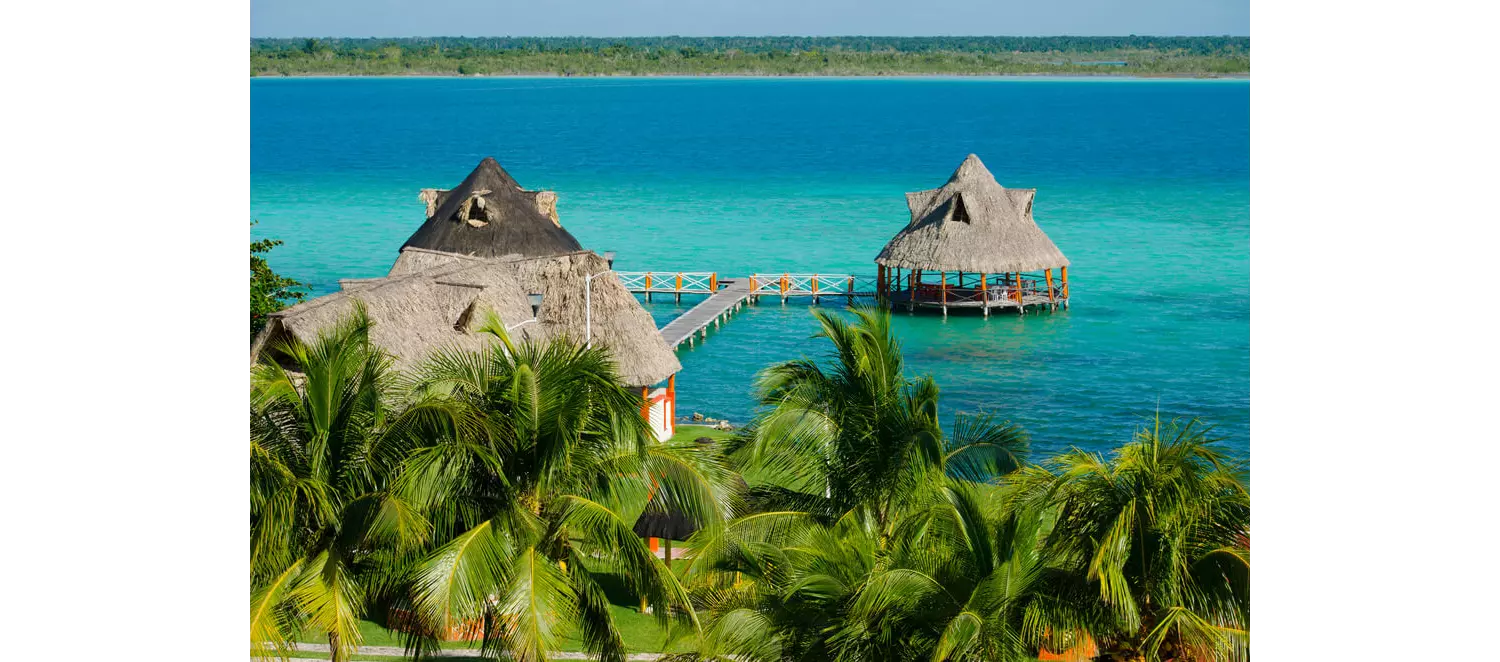 Mexiko schönste Orte: strohbedeckte Häuser auf dem Wasser in Bacalar.