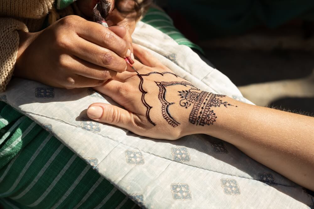 Henna: A woman getting her hand tattooed with henna 