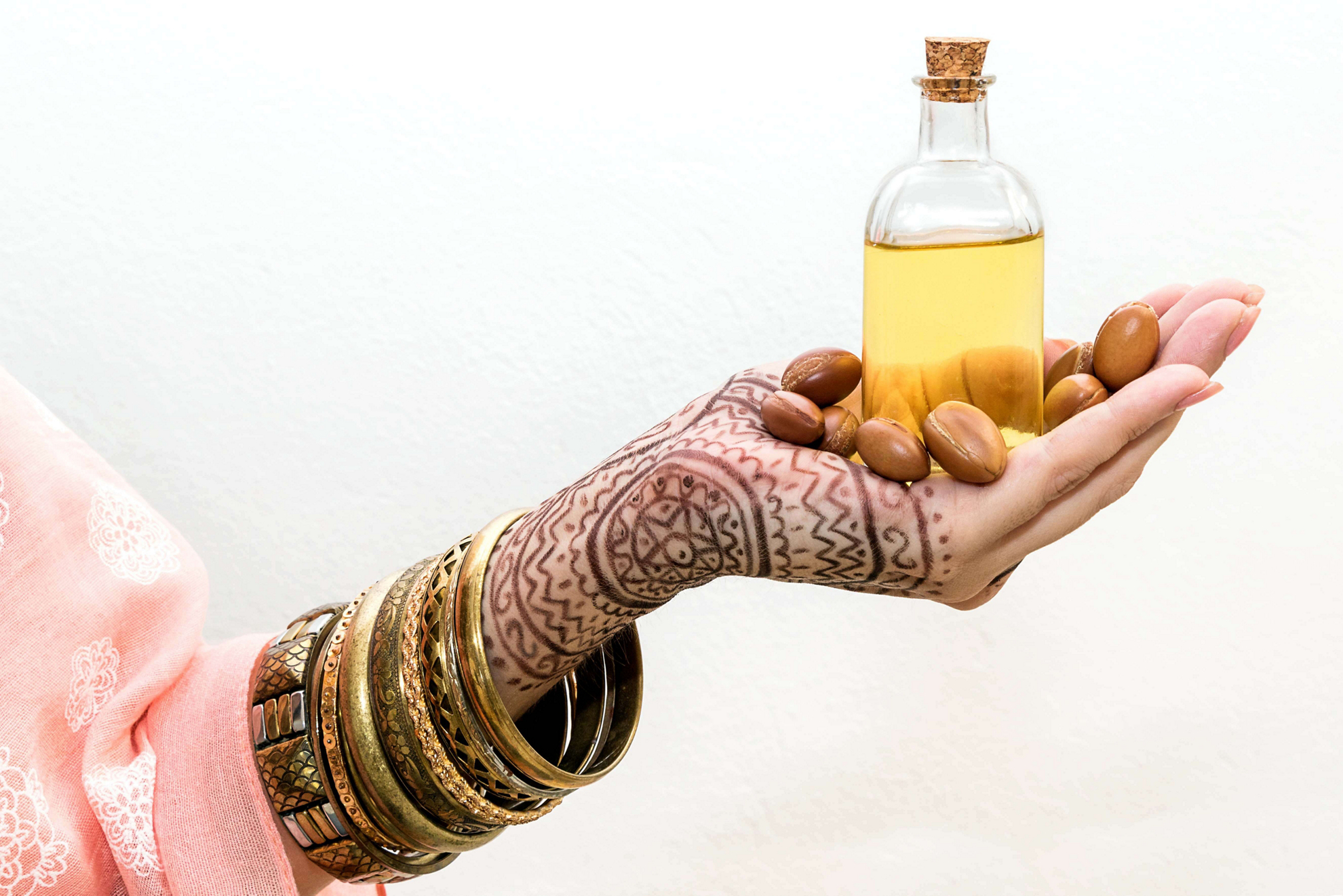 Moroccan beauty products: Henna tattooed hand holding a bottle of argan oil