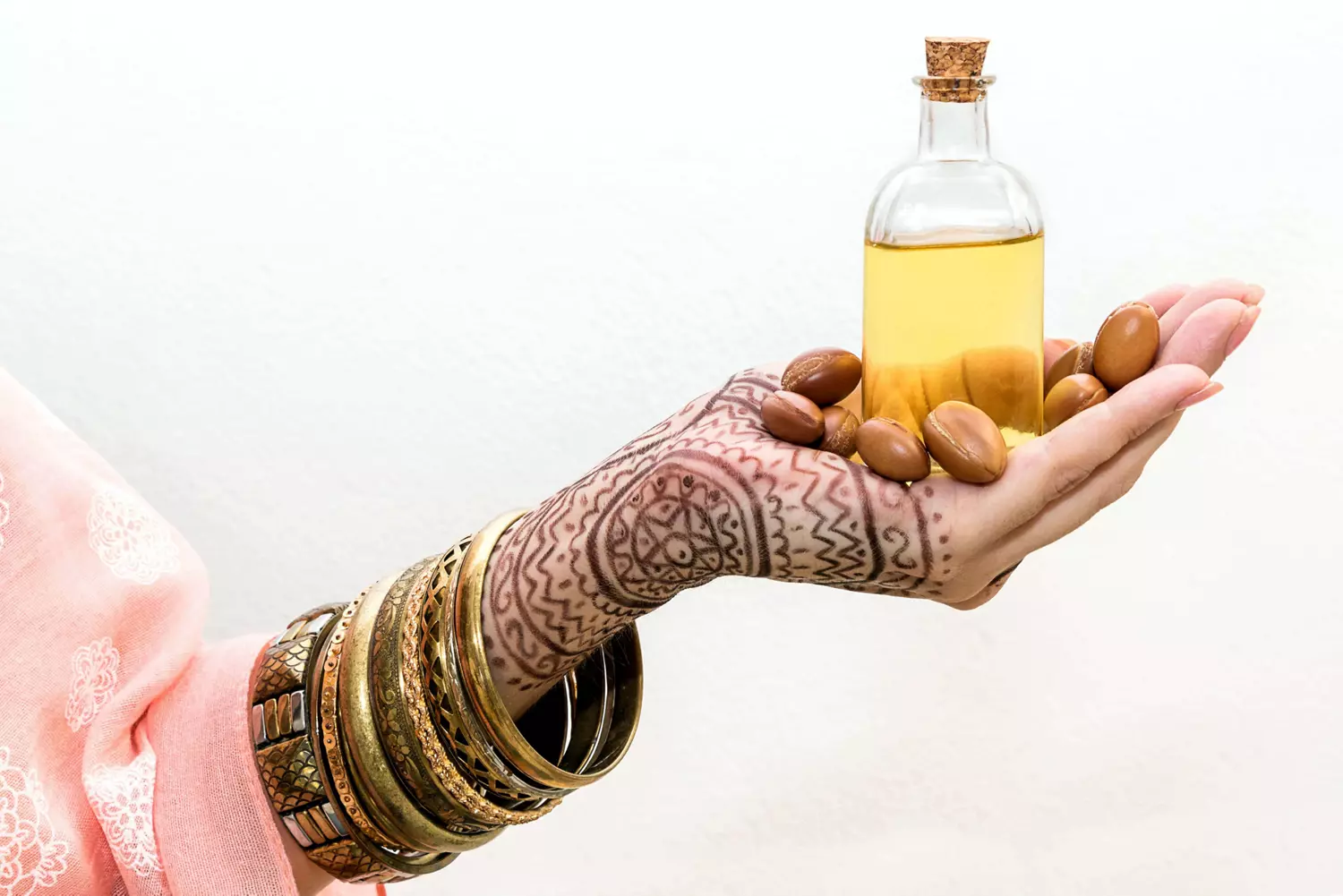 Moroccan beauty products: Henna tattooed hand holding a bottle of argan oil