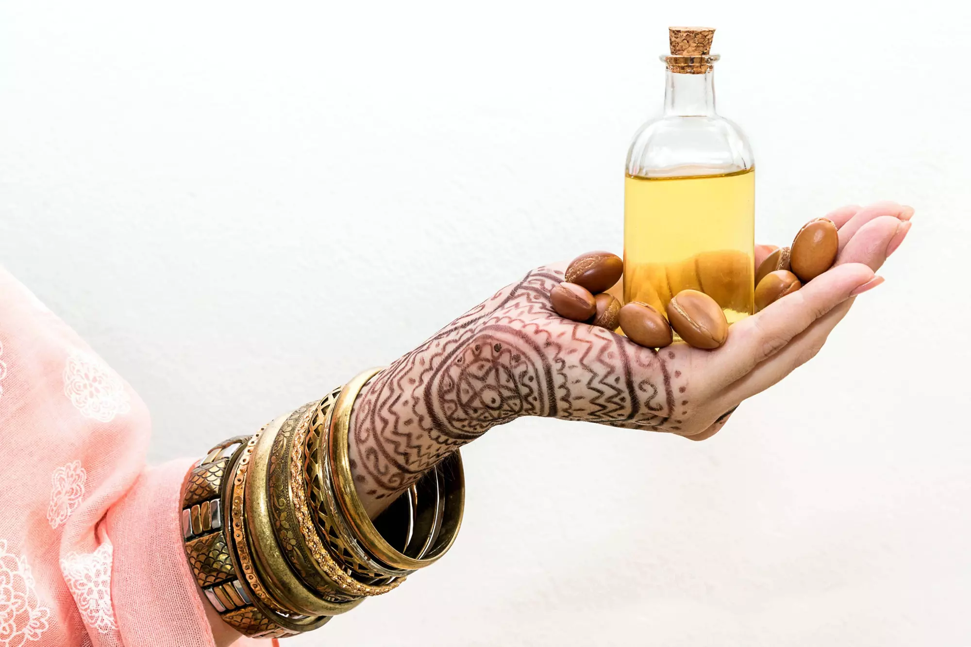 Moroccan beauty products: Henna tattooed hand holding a bottle of argan oil