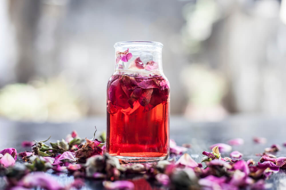 Rosewater: A small bottle of pink liquid with rose petals