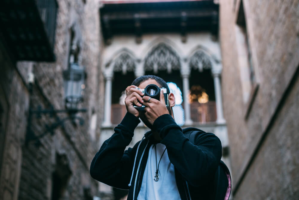 Museums in Barcelona: Close-up of a man holding a camera with a church in the background