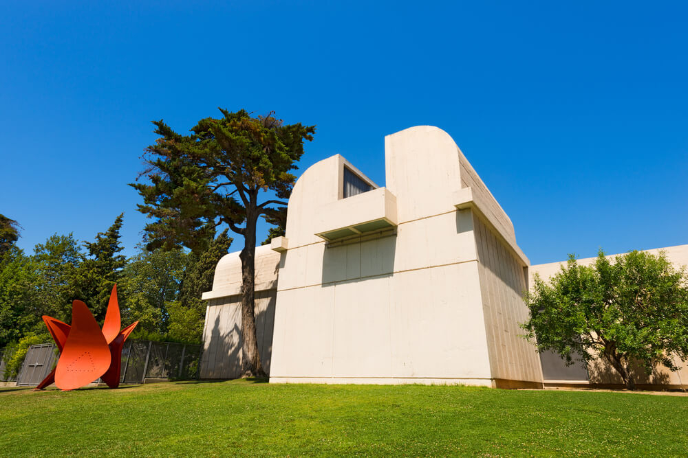 Joan Miró Foundation Barcelona: A white cement building on green grass next to a red statue