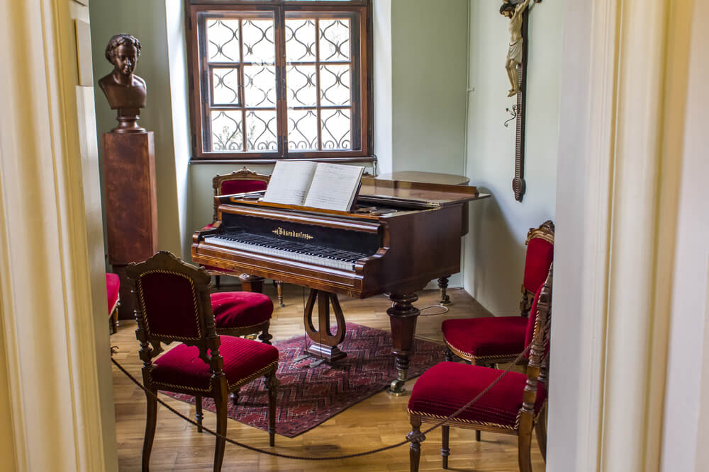 Antonín Dvořák Museum: A small piano in a room with two red chairs